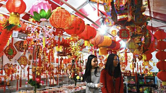 Hai cô gái đi giữa gian hàng bán đồ trang trí và đèn lồng nhiều màu sắc. Hội chợ không chỉ thu hút những người Việt mà còn cả người dân đến từ Nam California hay xa hơn như Canada. Ảnh: Los Angeles Times